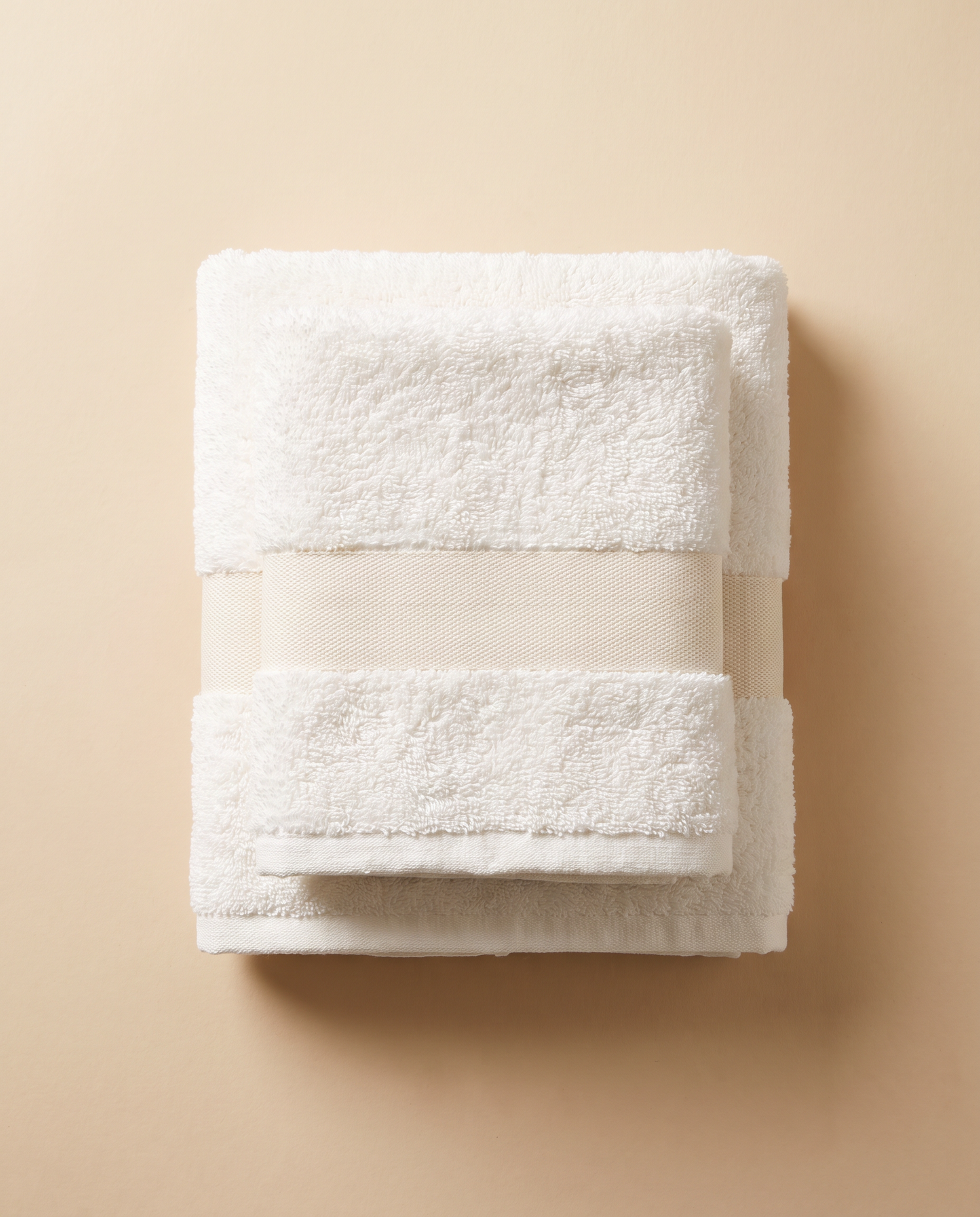 Pair of folded white cotton terry hand towels with a woven band