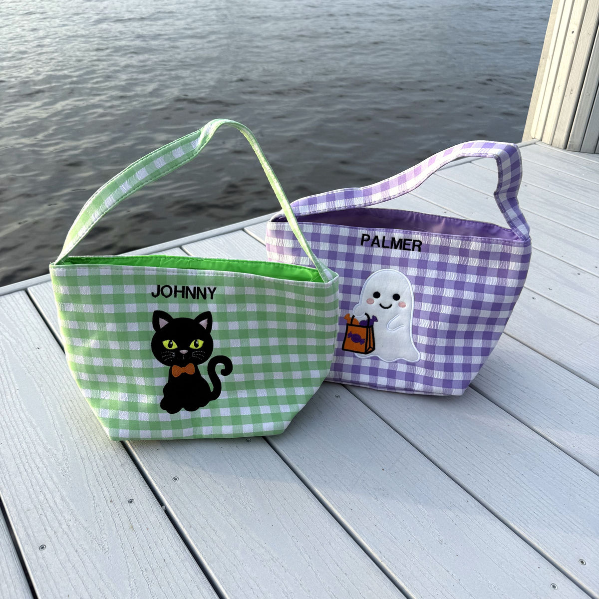 Green cat basket stitched JOHNNY and purple ghost basket stitched PALMER on a white dock at sunset