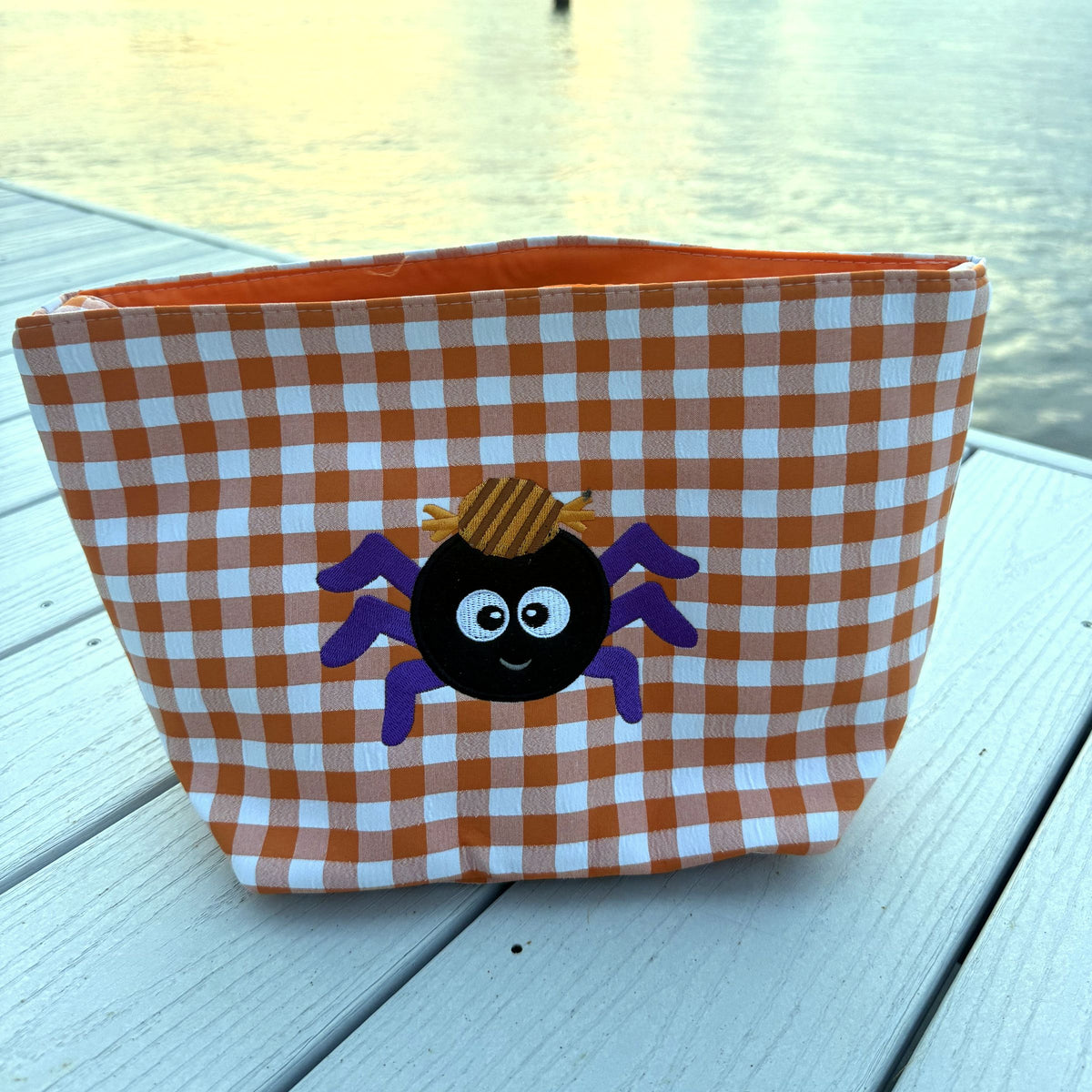 Orange gingham basket with a round black spider with purple legs