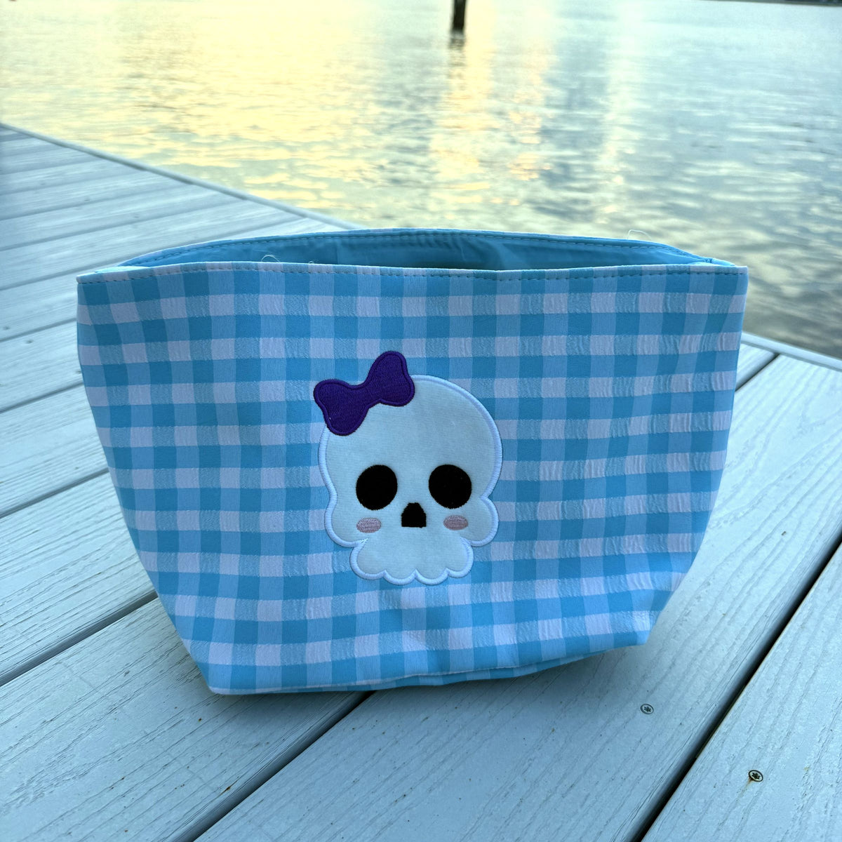 Blue gingham basket with a white skull wearing a purple bow